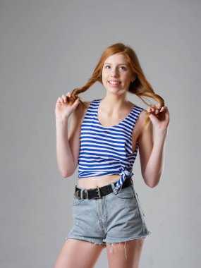 Gri arka planda uzun kızıl saçlı genç bir kız.