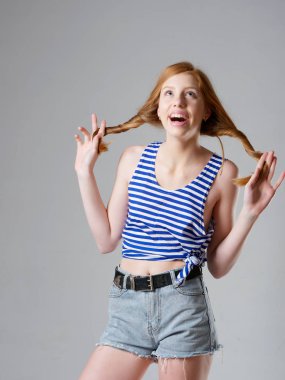 Gri arka planda uzun kızıl saçlı genç bir kız.