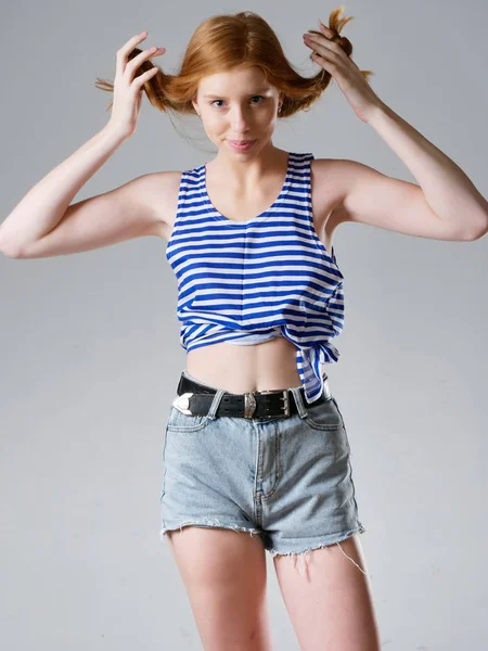 Chica joven con el pelo largo y rojo sobre un fondo gris —  Fotos de Stock