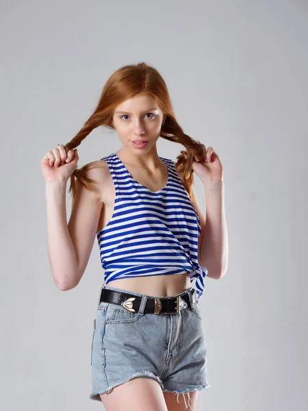 Chica joven con el pelo largo y rojo sobre un fondo gris —  Fotos de Stock