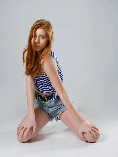 Fiatal lány hosszú vörös haj egy szürke háttér — Stock Fotó