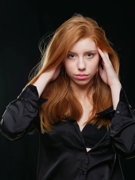 Jeune fille avec de longs cheveux rouges sur un fond noir — Photo