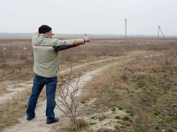 Молодий чоловік стріляє в рогатку в природі — стокове фото