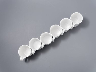 Gri arkaplandaki kompozisyonda yücelik için beyaz bardaklar