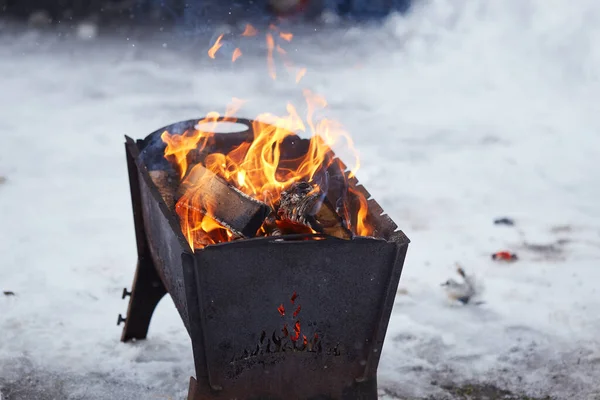 Hand with poker adjusts the coals in the brazier. Lighting the barbecue in the backyard in the winter. — Stock Photo, Image