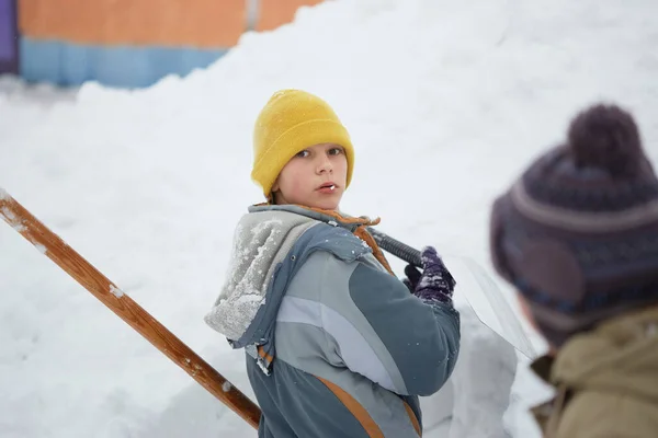 Захоплена дитина грає зі снігом у парку на білому сніговому тлі. Зимові діти в морозному зимовому парку . — стокове фото