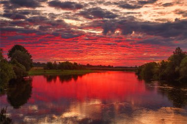 Nehrin üzerinde kırmızı mor gökyüzü bulutu ile güzel bir gün doğumu