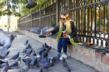 Güzel kız şehir güvercinlerini elleriyle besliyor.