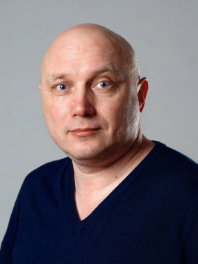 2020 'de gri arka planda kel, neşeli bir adamın portresi.