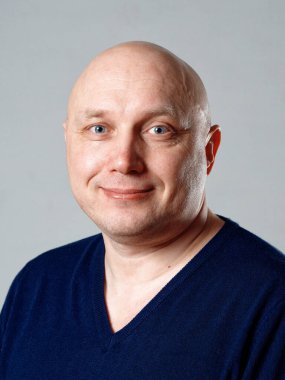 2020 'de gri arka planda kel, neşeli bir adamın portresi.