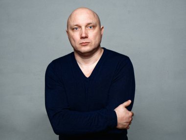 2020 'de gri arka planda kel, neşeli bir adamın portresi.