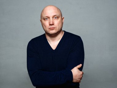 2020 'de gri arka planda kel, neşeli bir adamın portresi.