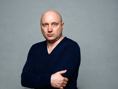 2020 'de gri arka planda kel, neşeli bir adamın portresi.