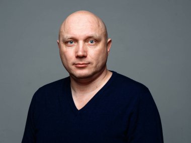 2020 'de gri arka planda kel, neşeli bir adamın portresi.