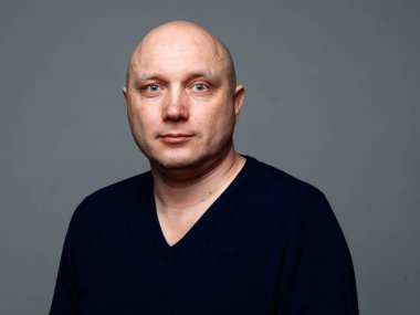 2020 'de gri arka planda kel, neşeli bir adamın portresi.