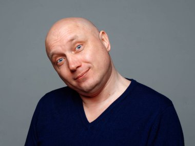 2020 'de gri arka planda kel, neşeli bir adamın portresi.