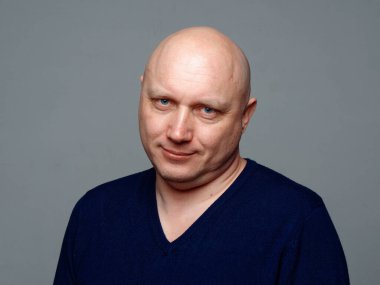 2020 'de gri arka planda kel, neşeli bir adamın portresi.