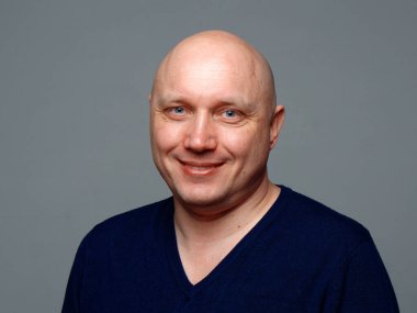 2020 'de gri arka planda kel, neşeli bir adamın portresi.