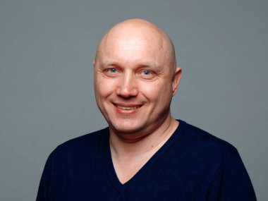 2020 'de gri arka planda kel, neşeli bir adamın portresi.