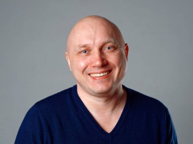 2020 'de gri arka planda kel, neşeli bir adamın portresi.