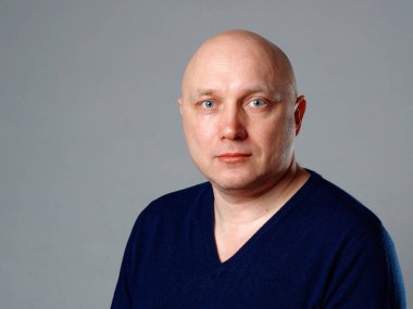 2020 'de gri arka planda kel, neşeli bir adamın portresi.