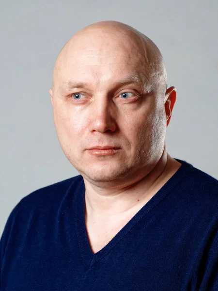 2020 'de gri arka planda kel, neşeli bir adamın portresi.