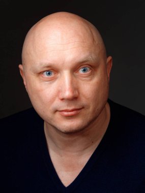 2020 'de siyah arka planda kel, neşeli bir adamın portresi.