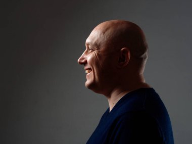 2020 'de siyah bir arka planda kel ve neşeli bir adamın portresi.