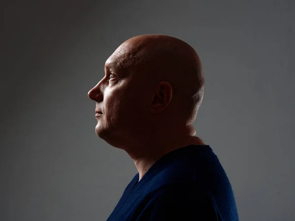 Portrait of a bald cheerful man in profile on a black background 2020