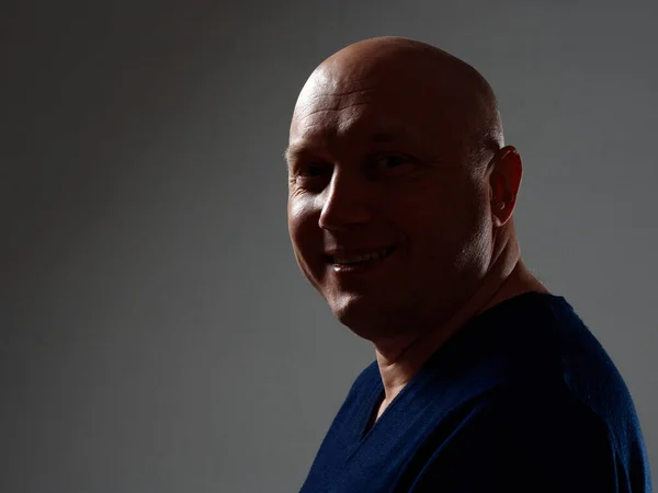 Portrait of a bald cheerful man in profile on a black background 2020