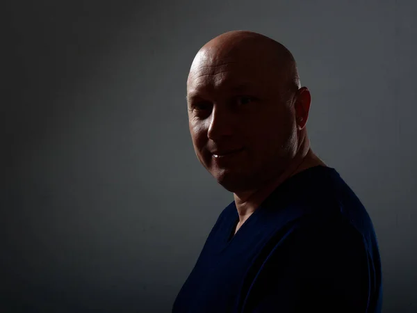 Portrait of a bald cheerful man in profile on a black background 2020