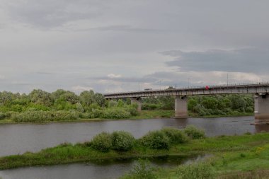 Gökyüzünde buğday tarlası üzerinde gök gürültülü bulutlar olan dramatik kırsal alan. Tarlada köy yolu