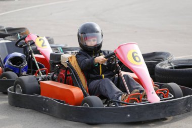 Çocuk yarış pistinde Go-kart arabasıyla hız yapıyor. Go kart popüler bir motor sporudur..