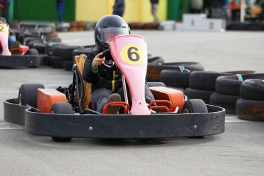Çocuk yarış pistinde Go-kart arabasıyla hız yapıyor. Go kart popüler bir motor sporudur..