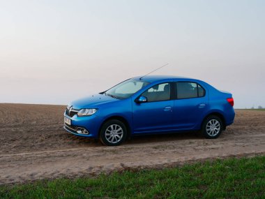Gomel, Belarus - 8 Nisan 2020: Mavi Renault Logan arabası 2020 'de gün doğumunda bir tarlada.