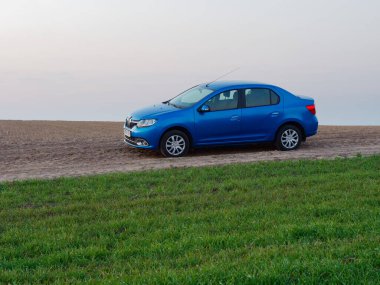 Gomel, Belarus - 8 Nisan 2020: Mavi Renault Logan arabası 2020 'de gün doğumunda bir tarlada.