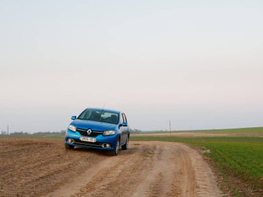 Gomel, Belarus - 8 Nisan 2020: Mavi Renault Logan arabası 2020 'de gün doğumunda bir tarlada.