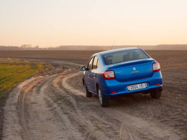 Gomel, Belarus - 8 Nisan 2020: Mavi Renault Logan arabası 2020 'de gün doğumunda bir tarlada.