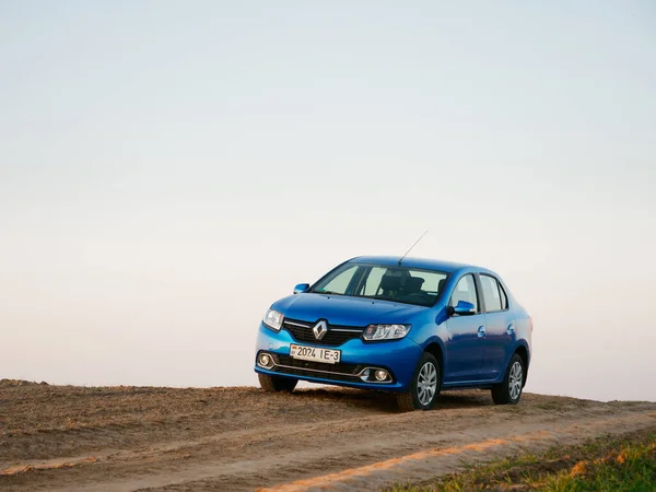 Gomel, Belarus - 8 Nisan 2020: Mavi Renault Logan arabası 2020 'de gün doğumunda bir tarlada.