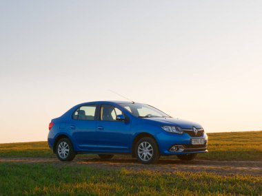 Gomel, Belarus - 8 Nisan 2020: Mavi Renault Logan arabası 2020 'de gün doğumunda bir tarlada.