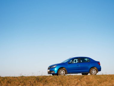 Gomel, Belarus - 8 Nisan 2020: Mavi Renault Logan arabası 2020 'de gün doğumunda bir tarlada.