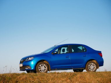 Gomel, Belarus - 8 Nisan 2020: Mavi Renault Logan arabası 2020 'de gün doğumunda bir tarlada.