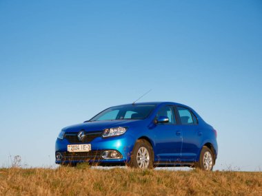 Gomel, Belarus - 8 Nisan 2020: Mavi Renault Logan arabası 2020 'de gün doğumunda bir tarlada.