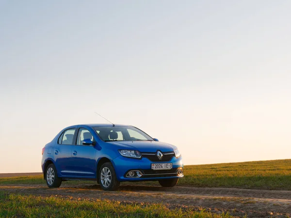Gomel, Belarus - 8 Nisan 2020: Mavi Renault Logan arabası 2020 'de gün doğumunda bir tarlada.