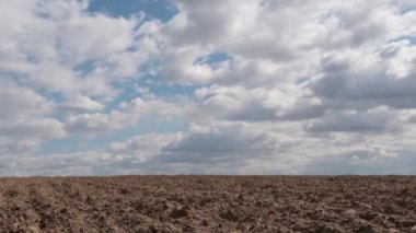 Mavi gökyüzünde süzülen bulutlar baharda verimli bir tarlanın üzerinde.