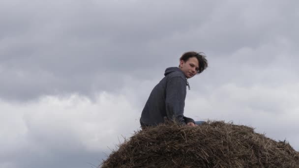 Teenager liegt in einem Strohhalm gegen den Himmel — Stockvideo