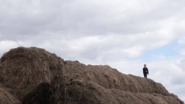 Barn leka med en hög halm mot himlen — Stockvideo