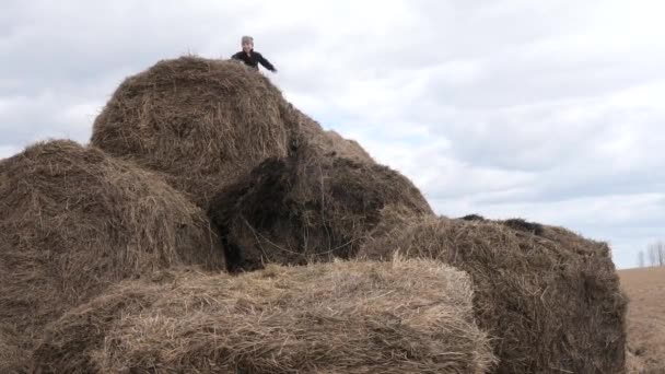 Enfant jouer avec une pile de paille contre le ciel — Video