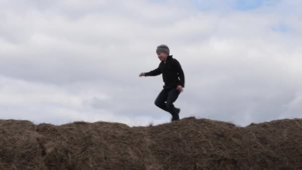 Child play with a stack of straw against the sky — Stock Video