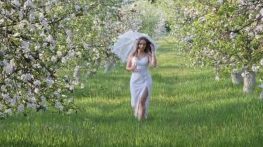 2020 bahçesinde çiçek açan elma ağaçlarında beyaz şemsiyeli bir kız.